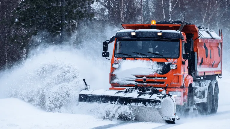 Snow plow truck clearing a snow covered road during a Capital Region winter storm