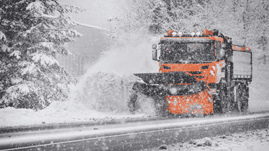 Snow plow truck removing heavy snow from roads to maintain clear and drivable routes.